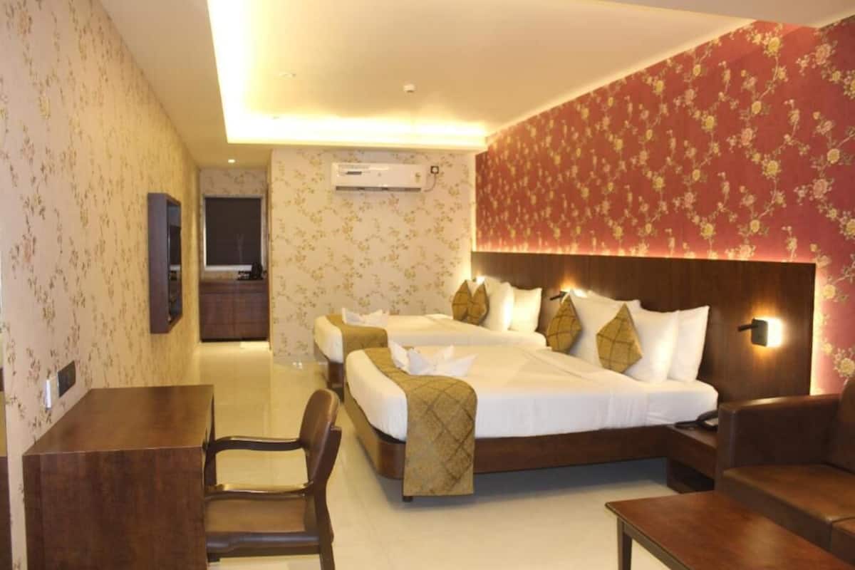 Habitación de hotel con dos camas, un escritorio, una silla y un sofá.