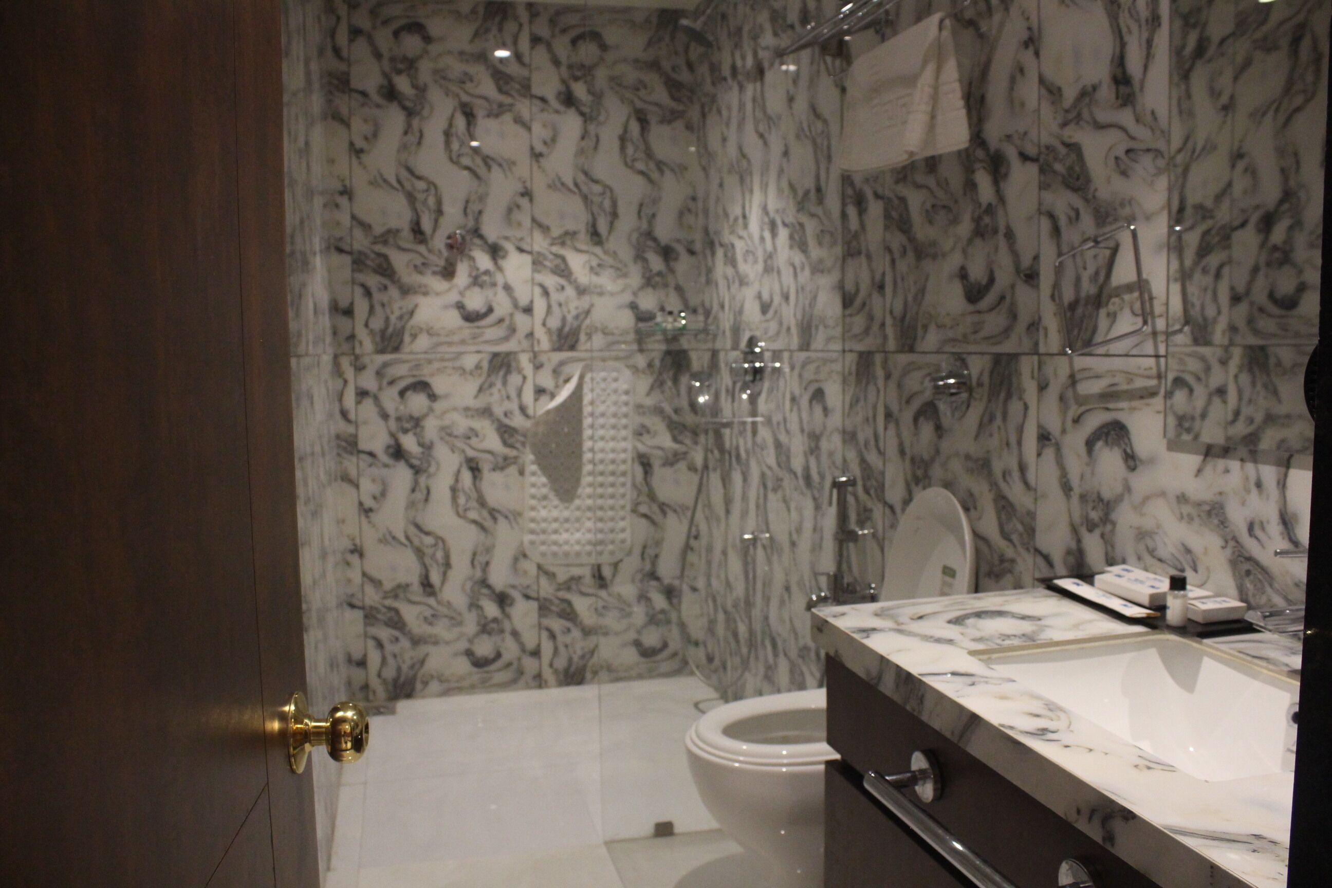 A bathroom with marble walls, a white toilet, and a sink with a mirror above it.