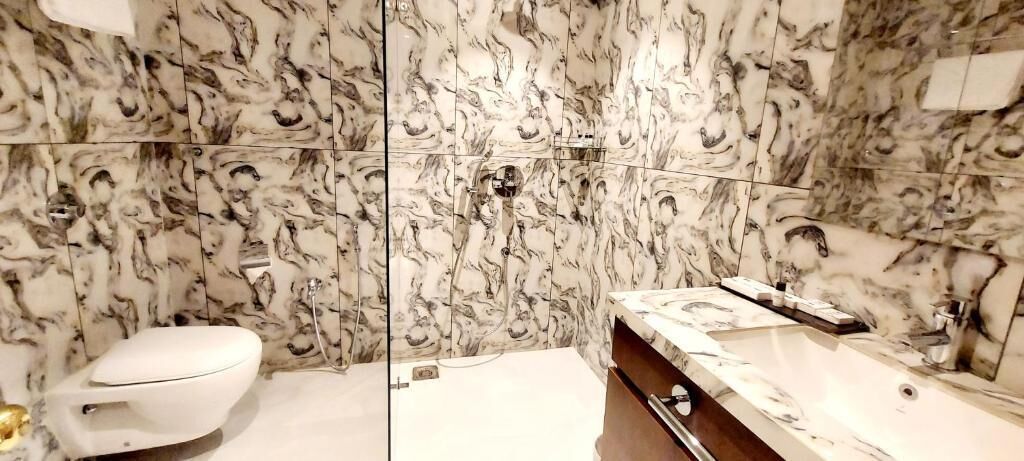 Un bagno con una parete in marmo, un water e un mobile con uno specchio.
