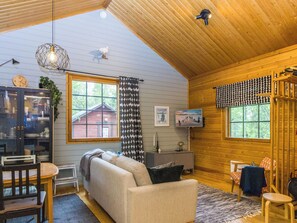A cozy cabin interior with a sofa, dining table, and a TV. - Riekkola by Interhome (Sodankylä)