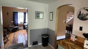 Un espacio habitable amplio con suelo de madera, una mesa de comedor y una cocina con un armario verde y una encimera blanca.