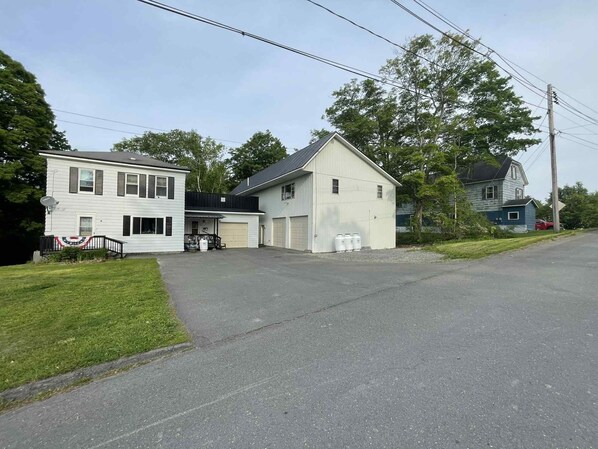 Une maison à deux étages avec un garage, une antenne parabolique et un petit jardin devant.