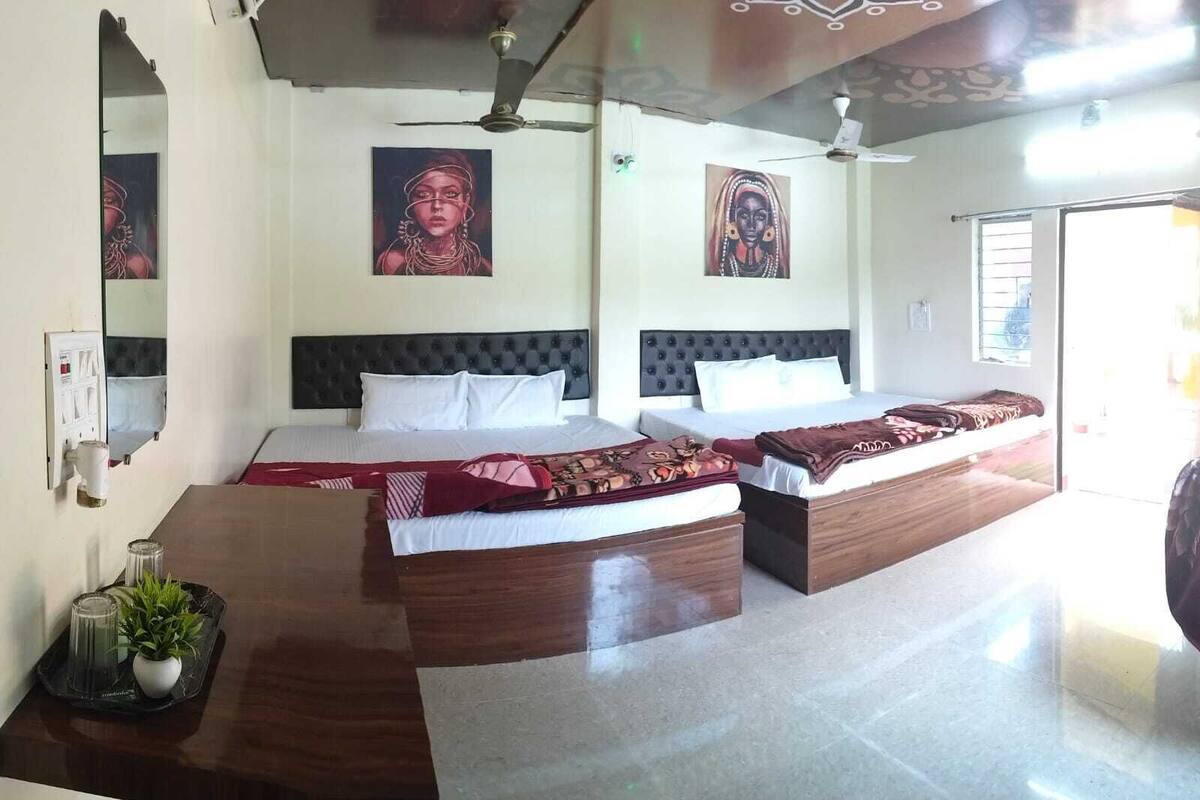 Quarto de hotel com duas camas, uma escrivaninha de madeira e um ventilador de teto.