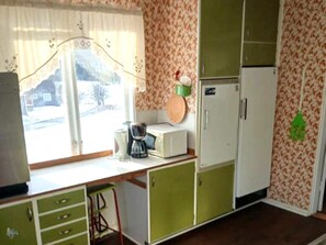 A kitchen with a window, a microwave, a refrigerator, and a sink.