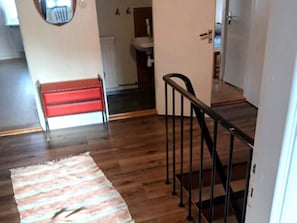 A wooden floor with a striped rug, a red bench, and a black railing.