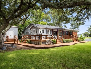 A single-story house with a deck, a garage, and a well-maintained lawn. - Little Oaks - Private Dock, Hot Tub, Sunset Views (Cedar Point)