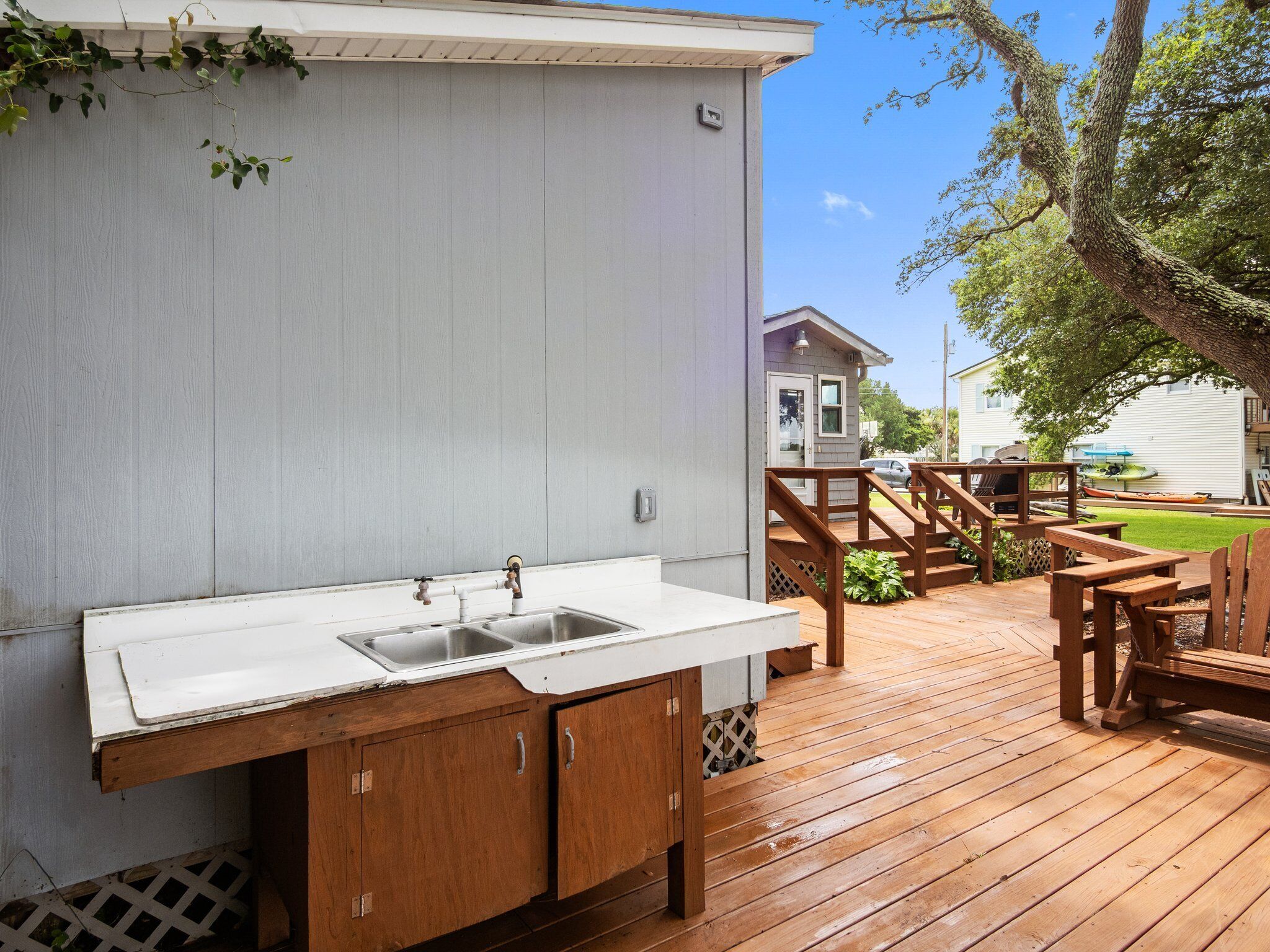 Une terrasse en bois avec un espace cuisine, comprenant un évier et des placards.