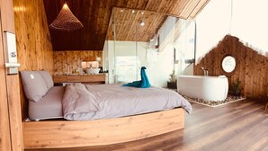 Ein modernes Schlafzimmer mit einem gewölbten Holzbett, einem großen Spiegel, einer hängenden Leuchte und einer Badewanne.