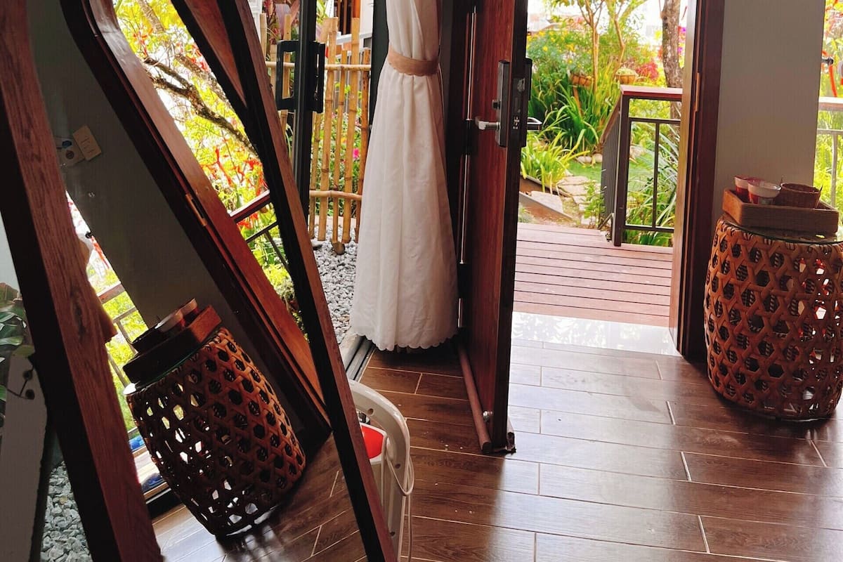 A room with a large window, a wooden door, and a hanging netted structure.