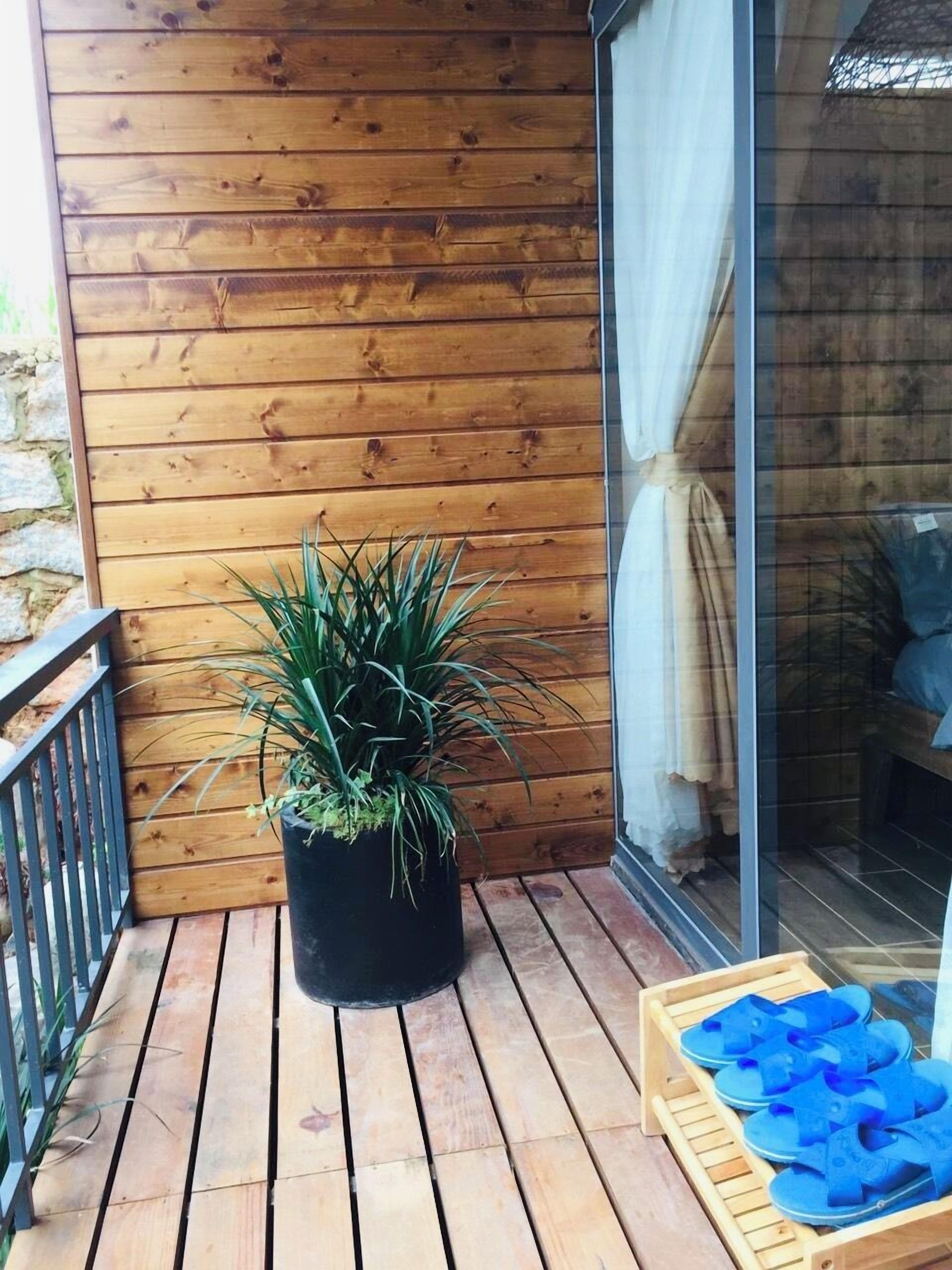 Un terrazzino in legno con una pianta in vaso e un porta scarpe di legno.