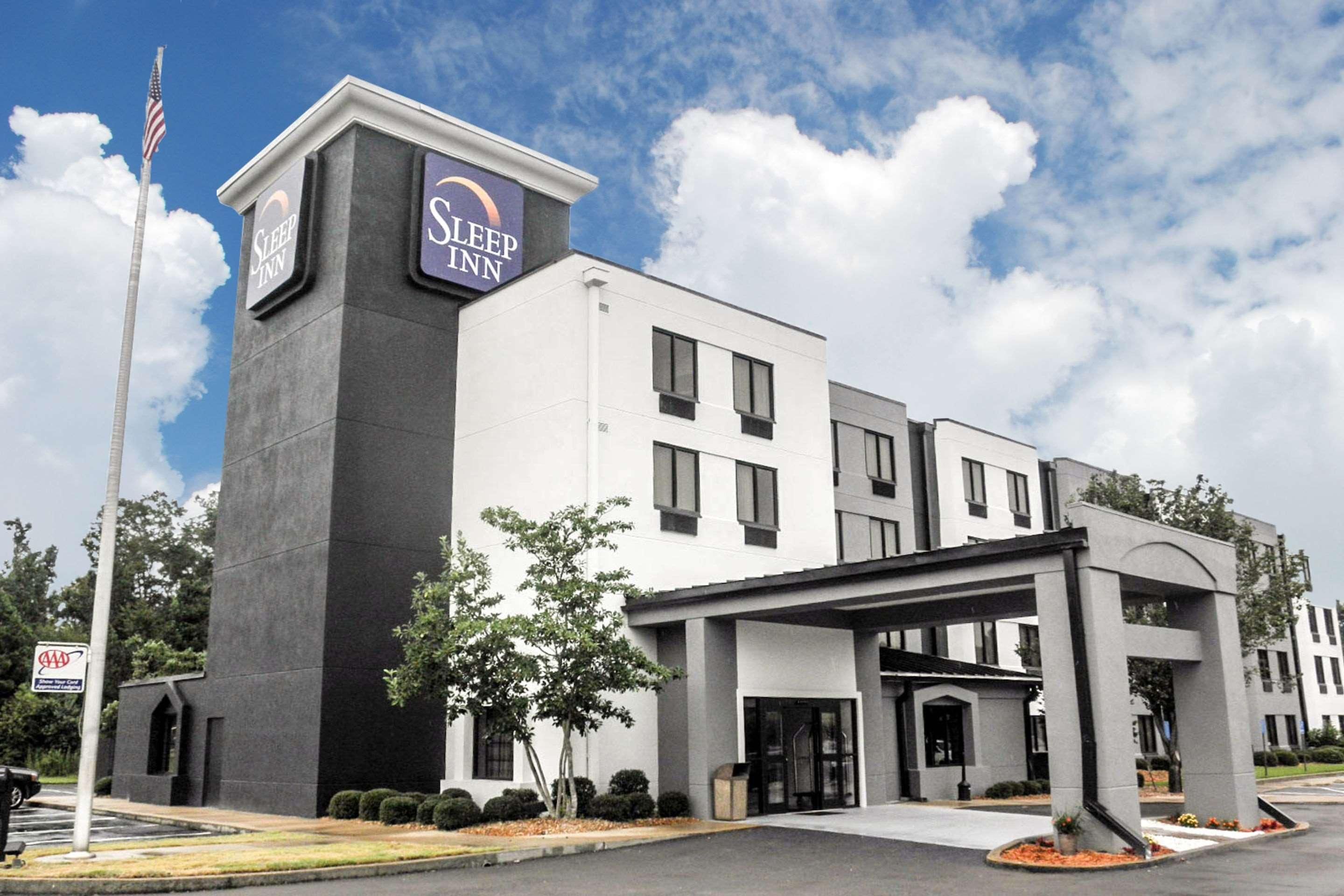 A Sleep Inn hotel with a modern facade, a flagpole, and a well-maintained entrance area.