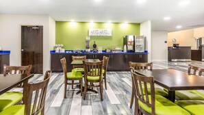 Una habitación de hotel con comedor, kitchenette y una cama.