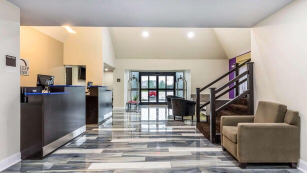 Un vestíbulo de hotel con una recepción, una escalera y una zona de estar.