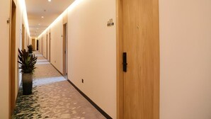 A hotel hallway with wooden doors, numbered room signs, and a carpeted floor. - Greentree Inn Nanjing Baijiahu Express Hotel (Nanjing)
