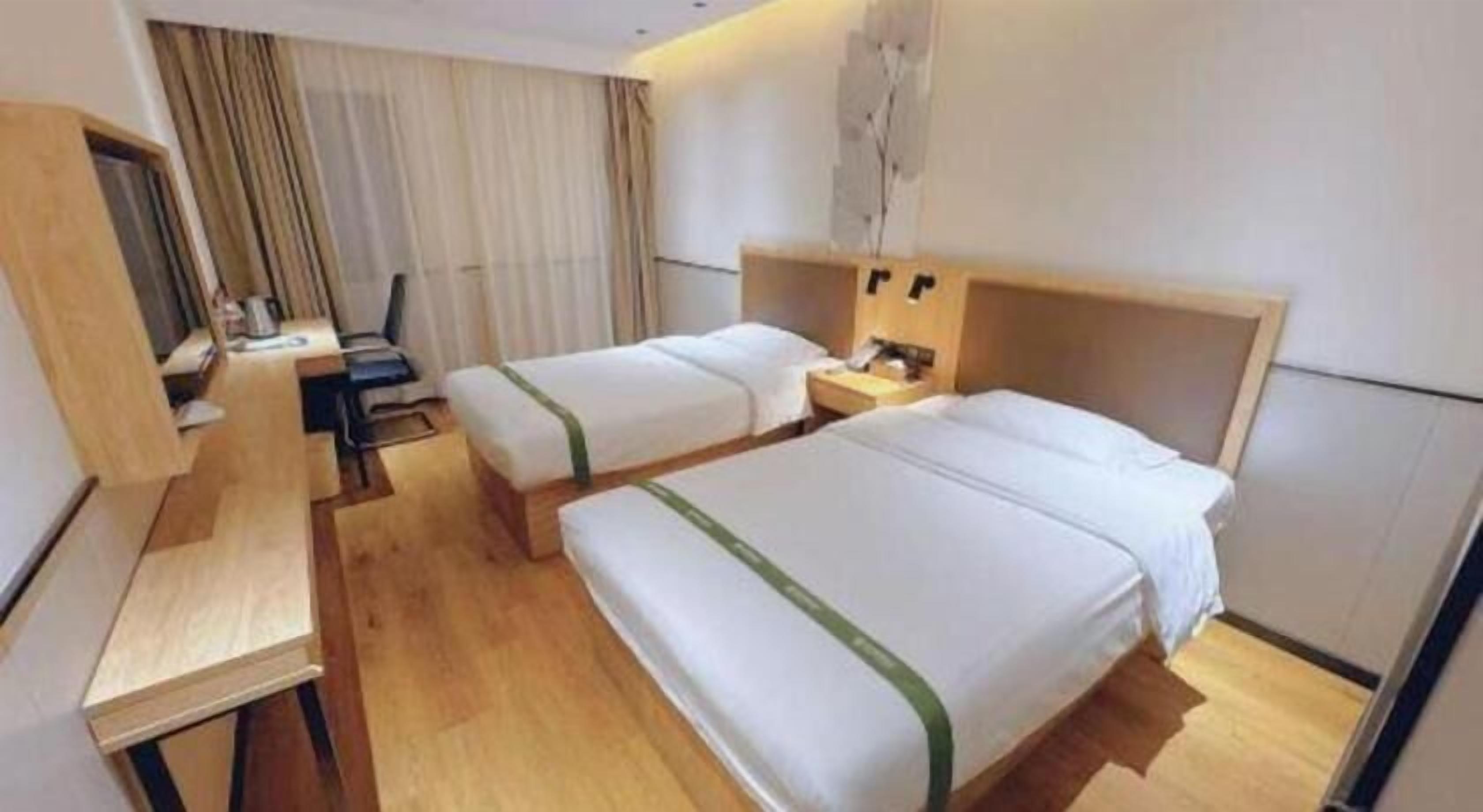 A hotel room with two beds, a desk, and a chair.