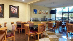 Un restaurante con sillas y mesas de madera, una zona de bar y obras de arte en las paredes.