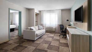 Una habitación de hotel moderna con una cama grande, un sofá, un escritorio y un televisor.