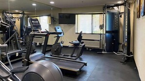Un gimnasio con cintas de correr, elípticas y equipo de levantamiento de pesas.