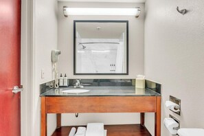 Une salle de bain avec un meuble-lavabo en bois, un miroir, un lavabo, une douche et des toilettes.