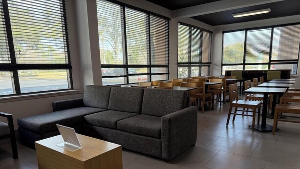 A modern interior with a sofa, tables, and chairs arranged for dining. - Wingate by Wyndham Jacksonville FL (Jacksonville)
