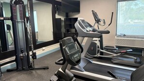 A gym with exercise equipment, a television, and a window with a view. - Wingate by Wyndham Jacksonville FL (Jacksonville)