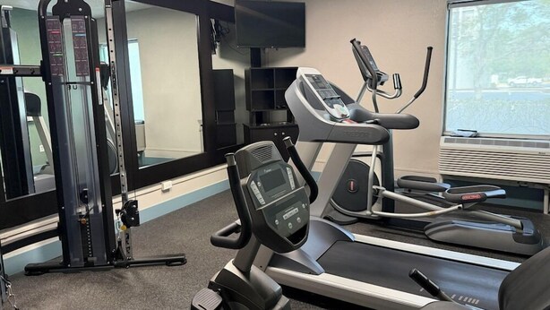 A gym with exercise equipment, a television, and a window with a view. - Wingate by Wyndham Jacksonville FL (Jacksonville)