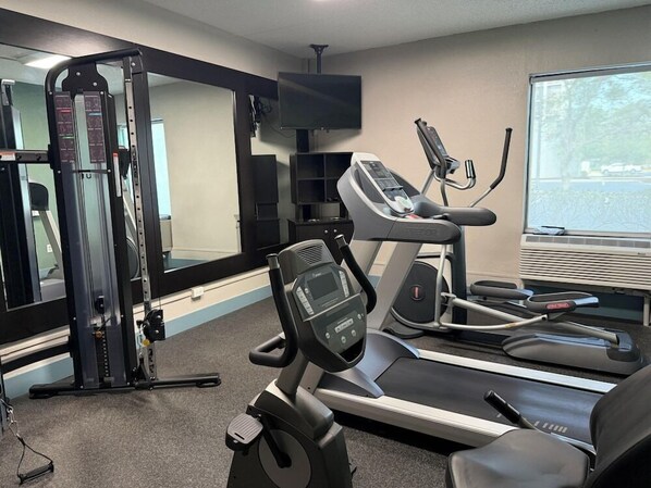 A gym with exercise equipment, a television, and a window with a view. - Wingate by Wyndham Jacksonville FL (Jacksonville)