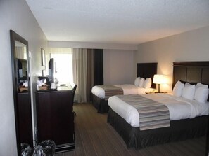 A hotel room with two beds, a desk, a mirror, and a window with curtains. - Wingate by Wyndham Jacksonville FL (Jacksonville)