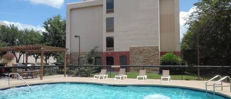A hotel named 'Country Inn & Suites' with a swimming pool, lounge chairs, and a covered patio area.