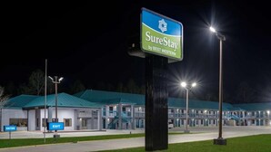 Ein BEST WESTERN SureStay Hotel bei Nacht mit gut beleuchtetem Eingang und einem Gebäude mit blauem Dach.