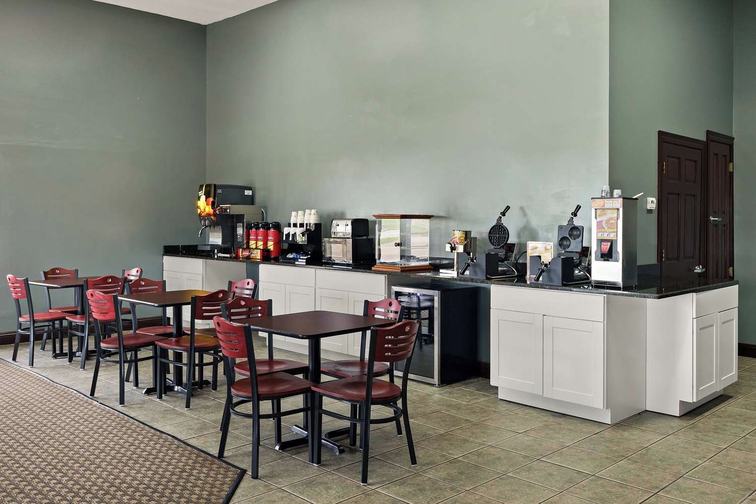 A restaurant with a counter, seating, and kitchen equipment.