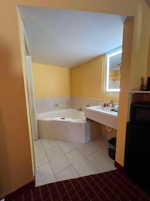 A bathroom with a bathtub, a sink, and a mirror. - Surestay by Best Western Gulfport (Gulfport)