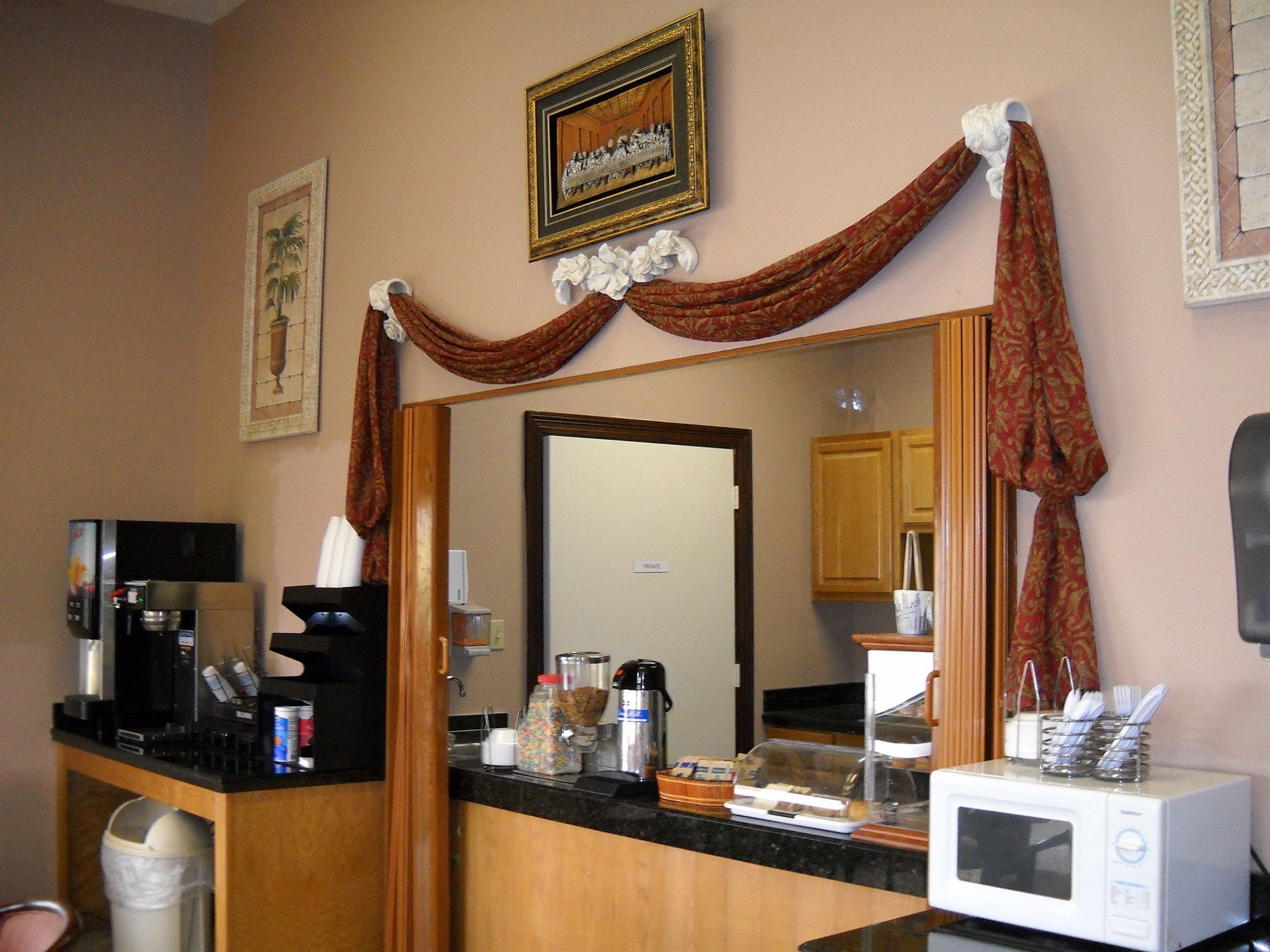 A hotel room with a kitchenette, a microwave, a coffee maker, and a trash can.