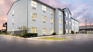 Un hotel de varios pisos con techo plano, ventanas grandes y un estacionamiento.