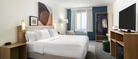 A hotel room with a large bed, bedside tables, a TV, a wardrobe, and a window with curtains.