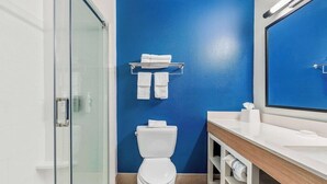 A modern bathroom with a white toilet, a glass shower enclosure, and a blue accent wall.