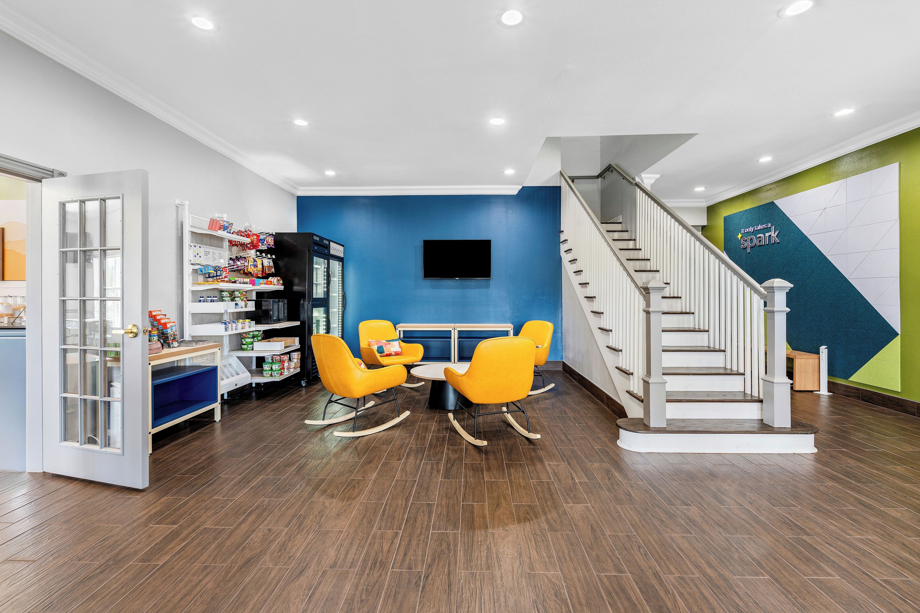 A modern interior with a dining area, a staircase, and a wall-mounted TV.