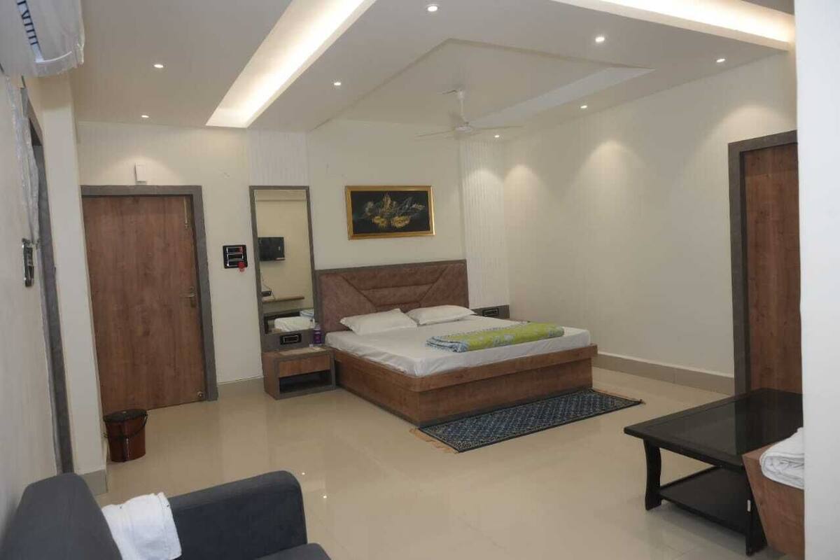 Une chambre moderne avec un grand lit, des tables de chevet, un bureau et un ventilateur de plafond.