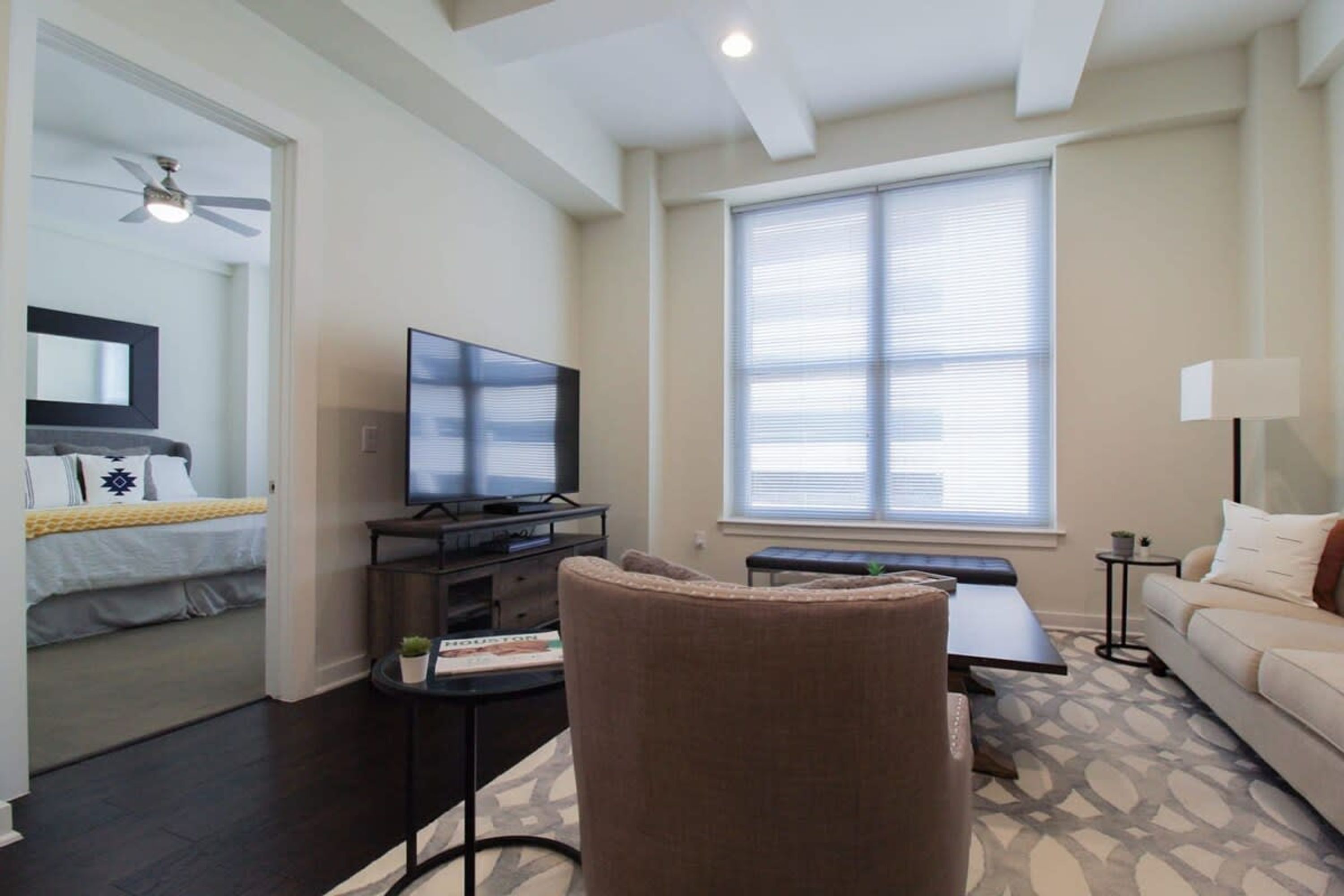 A modern living room with a flat-screen TV, a sofa, a coffee table, and a ceiling fan.
