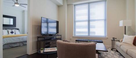 A modern living room with a flat-screen TV, a sofa, a coffee table, and a ceiling fan.