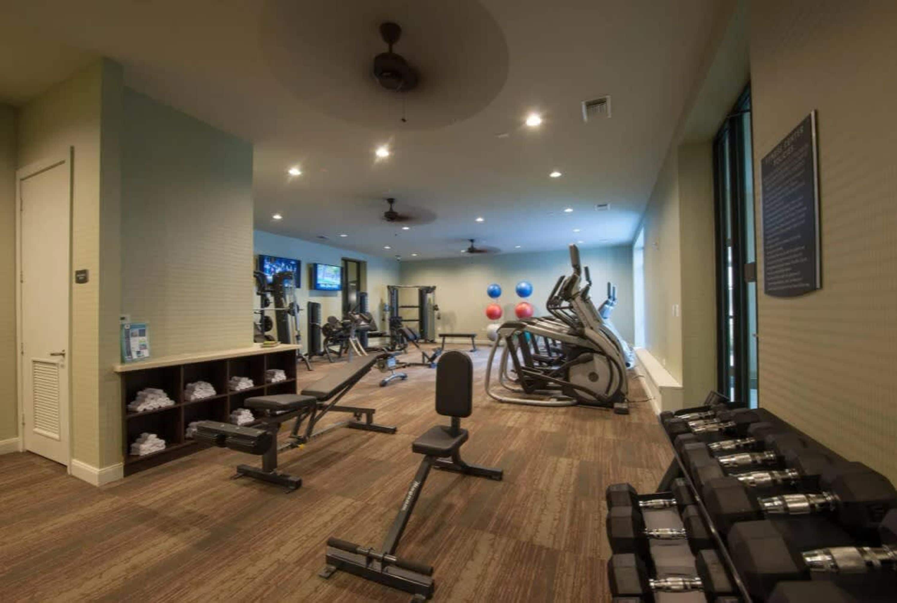 A gym with various exercise equipment, a television, and a wall-mounted sign.