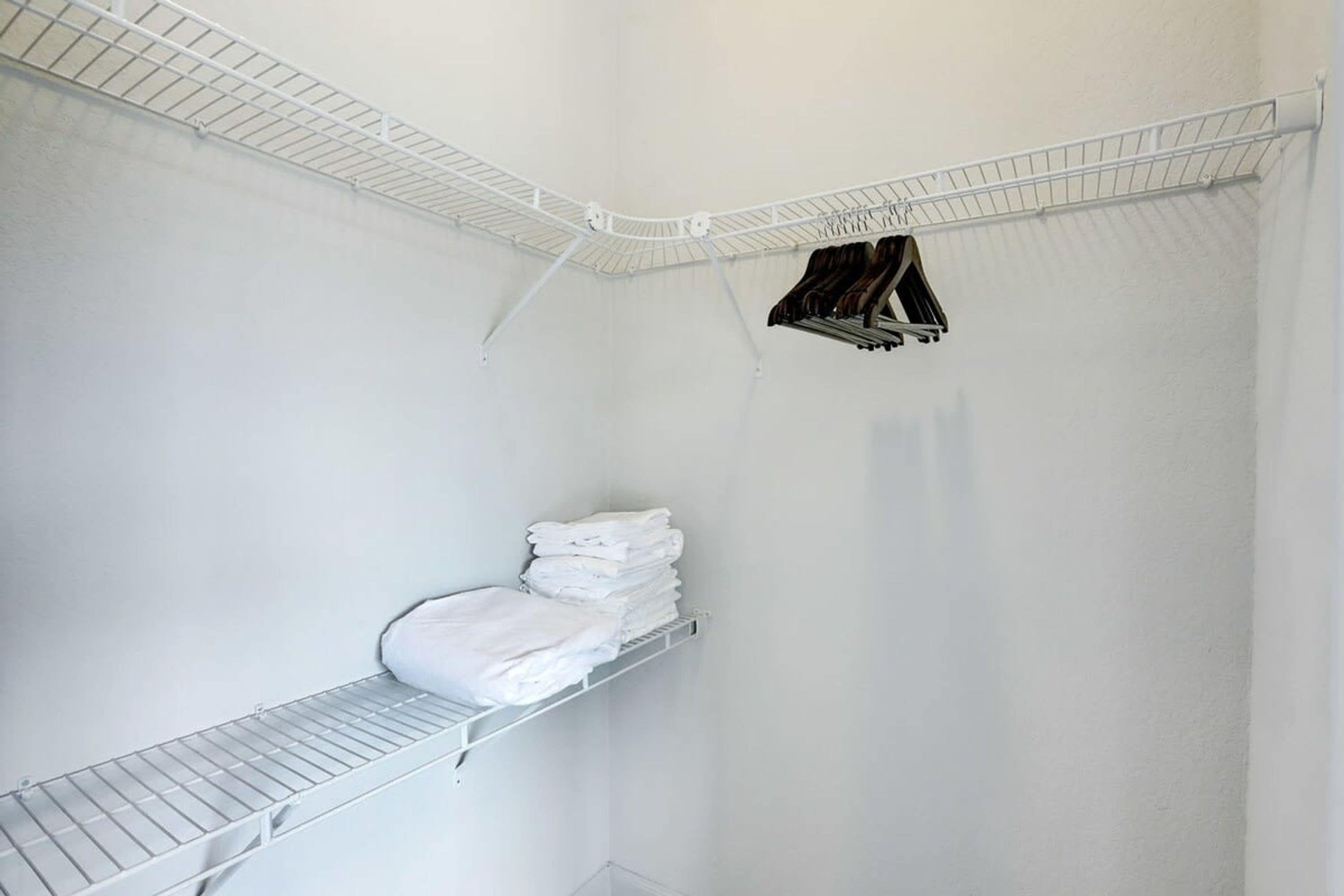 Een hoek van een kamer met een witte muur, een metalen plank en een hangrek.