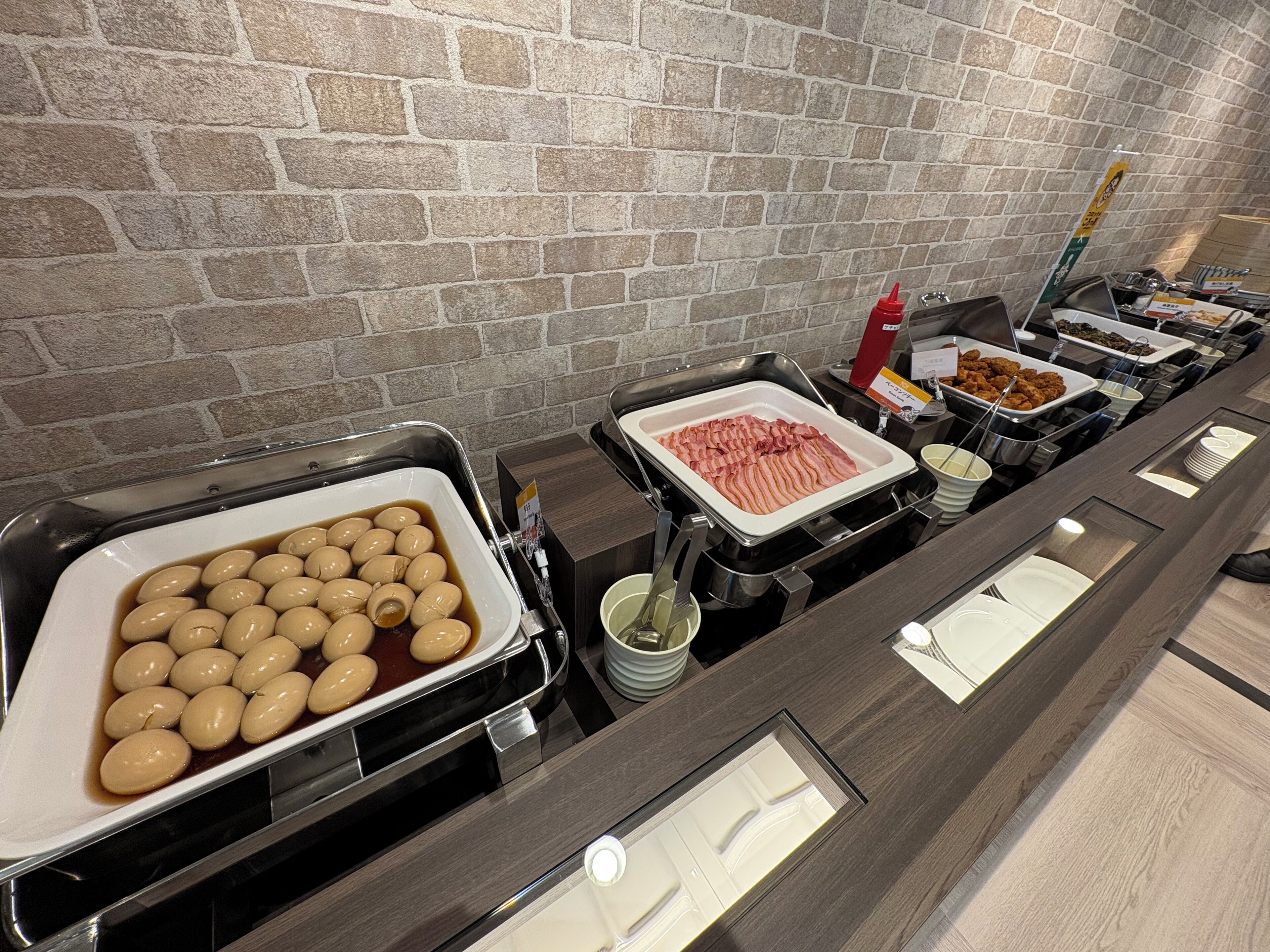 Un bufé con diversos alimentos, incluyendo una bandeja de huevos, tocino y otros platos.