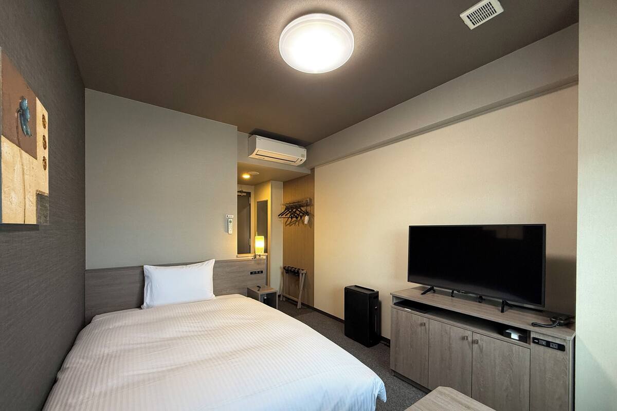 A hotel room with a bed, a TV, a desk, and a wardrobe.