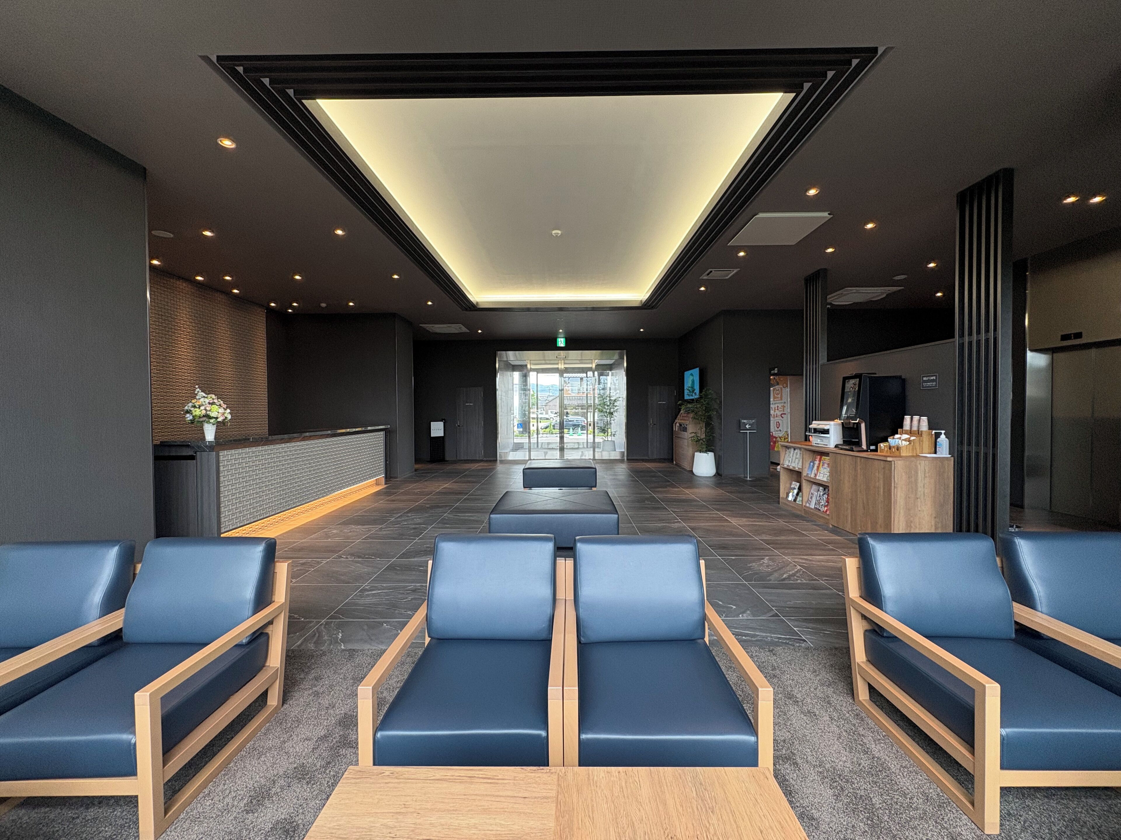 Um lobby moderno com balcão de recepção, área de estar e espaço para café.