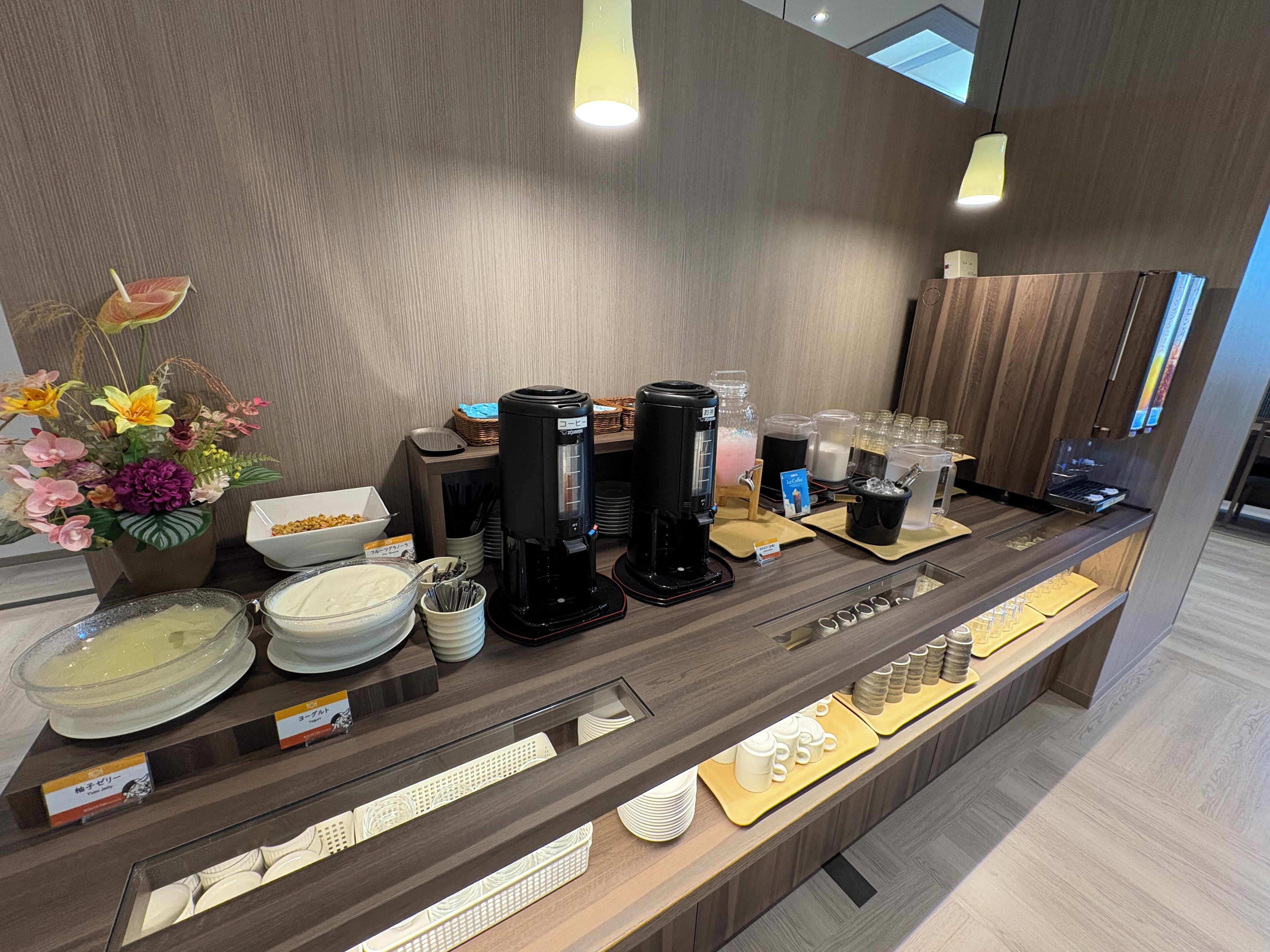 A hotel reception area with a coffee station, tea station, and a display of white ceramic tableware.