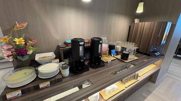 A hotel reception area with a coffee station, tea station, and a display of white ceramic tableware.