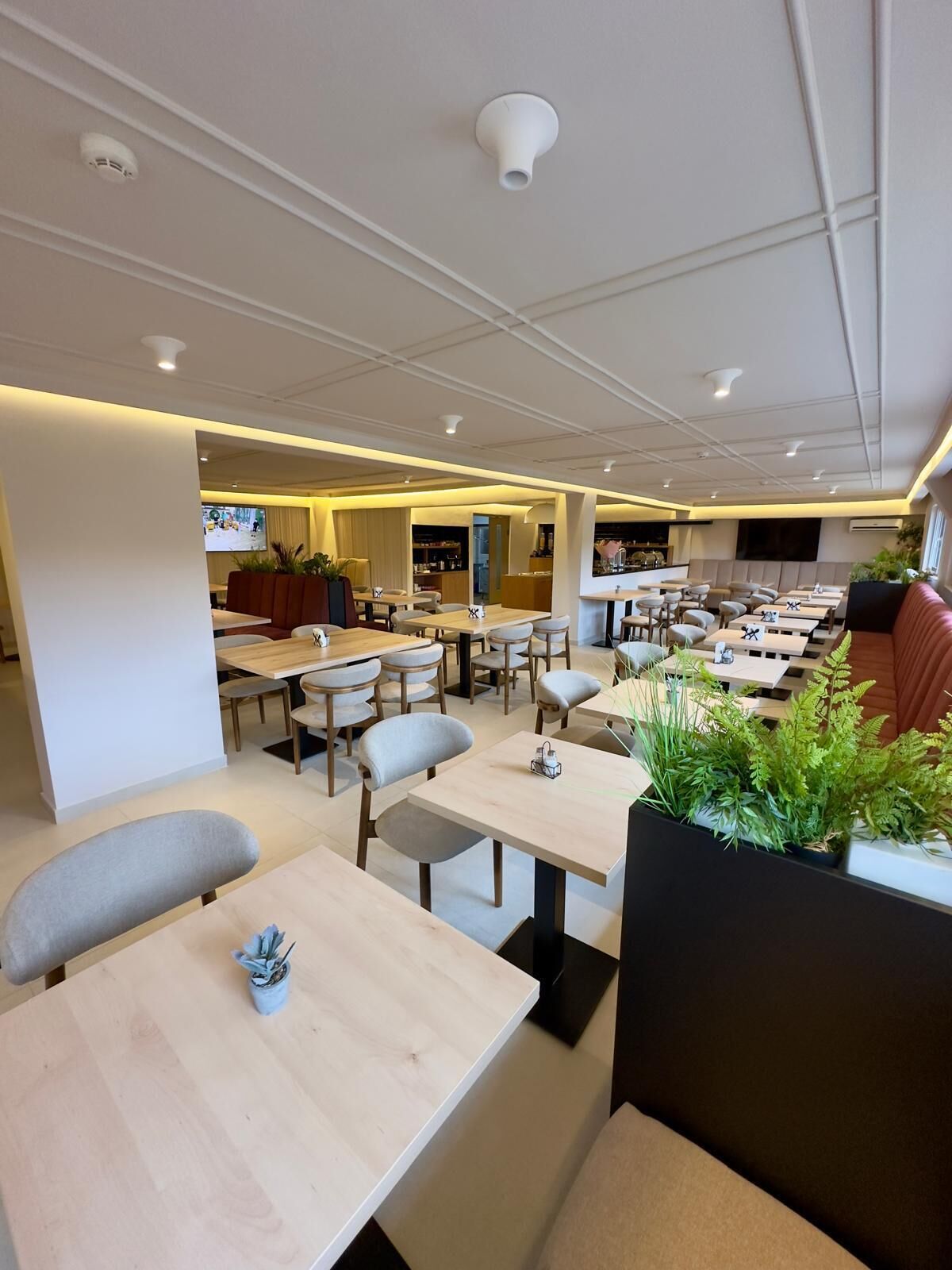 Un restaurante moderno con varias zonas de estar, incluyendo cabinas y mesas, y una zona de bar central.