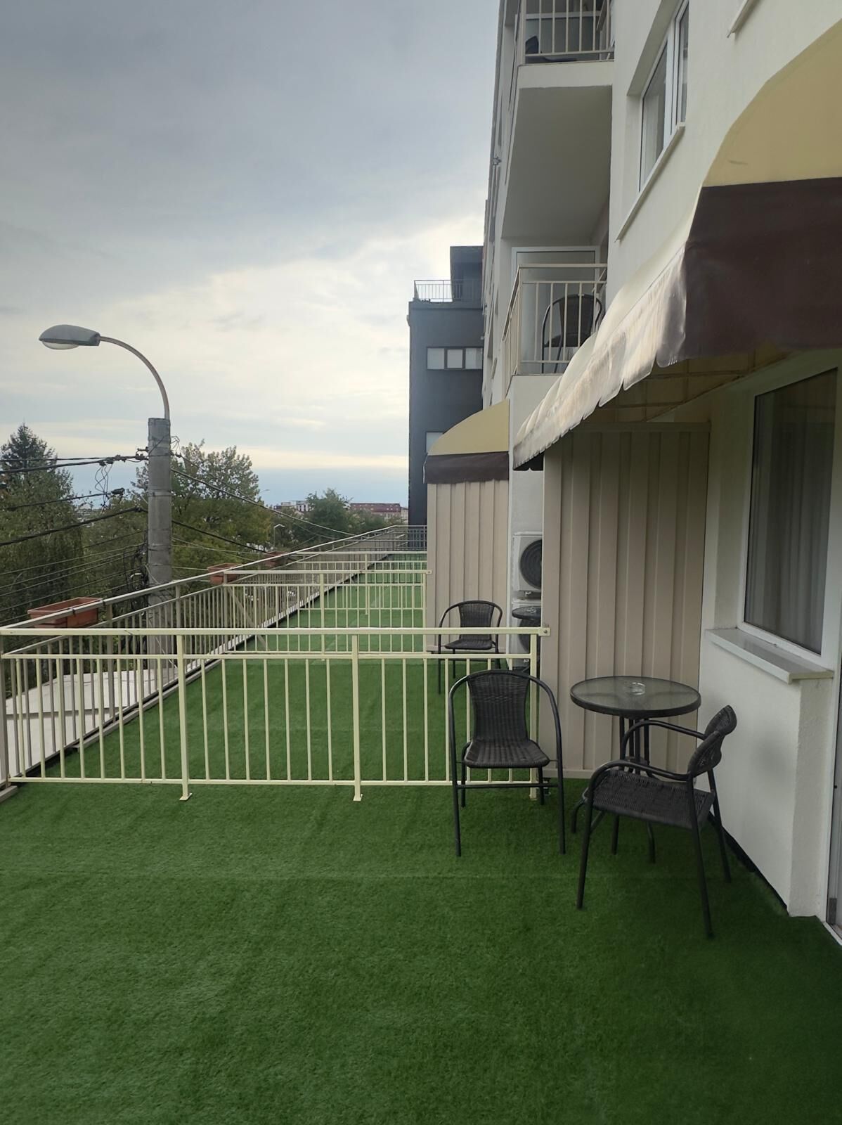 A balcony with artificial grass, two chairs, and a table.