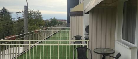 A balcony with artificial grass, two chairs, and a table.